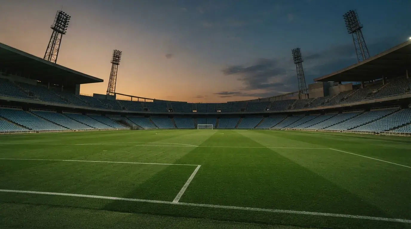 Een leeg voetbalstadion met lichtmasten bij schemering