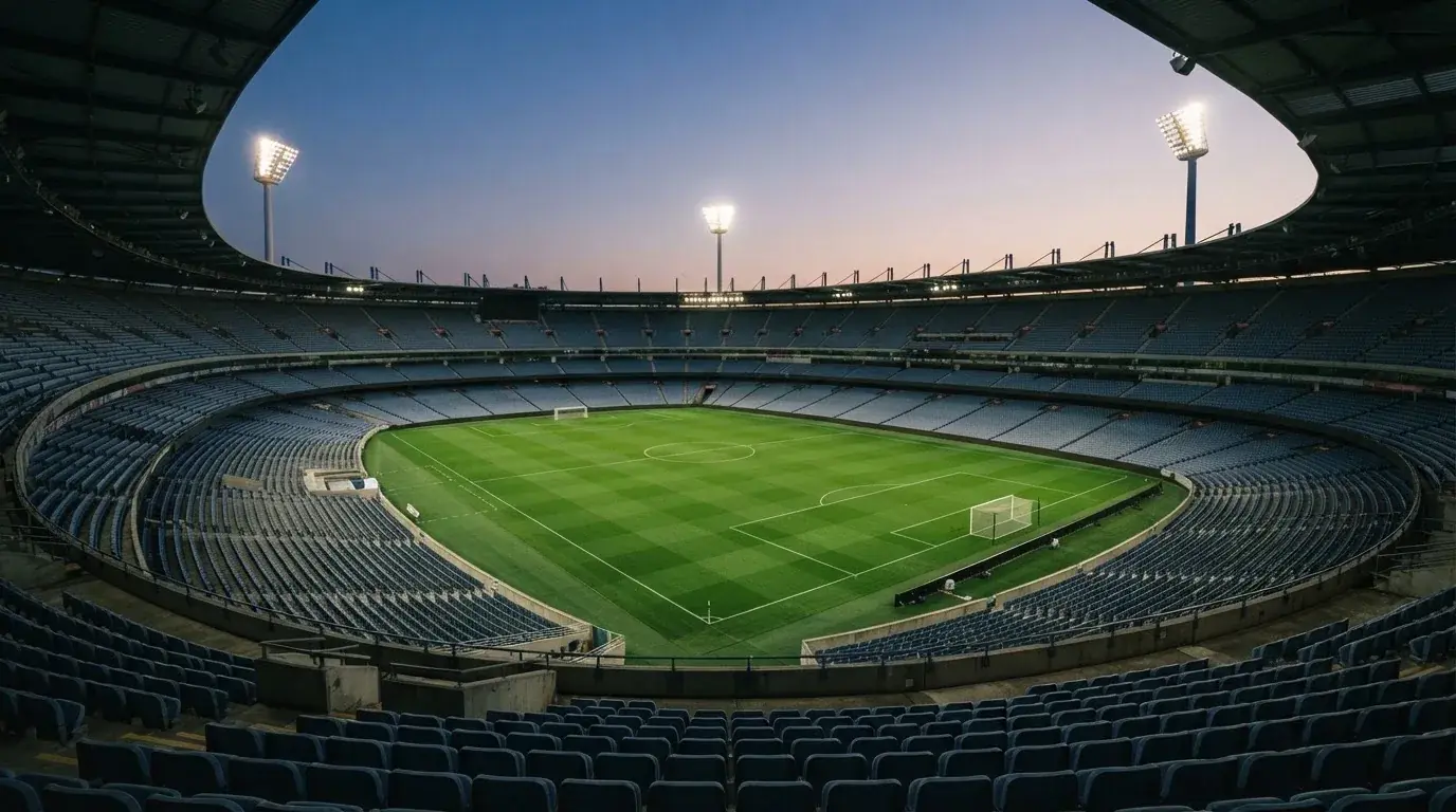 Een leeg voetbalstadion met lichtmasten bij schemering