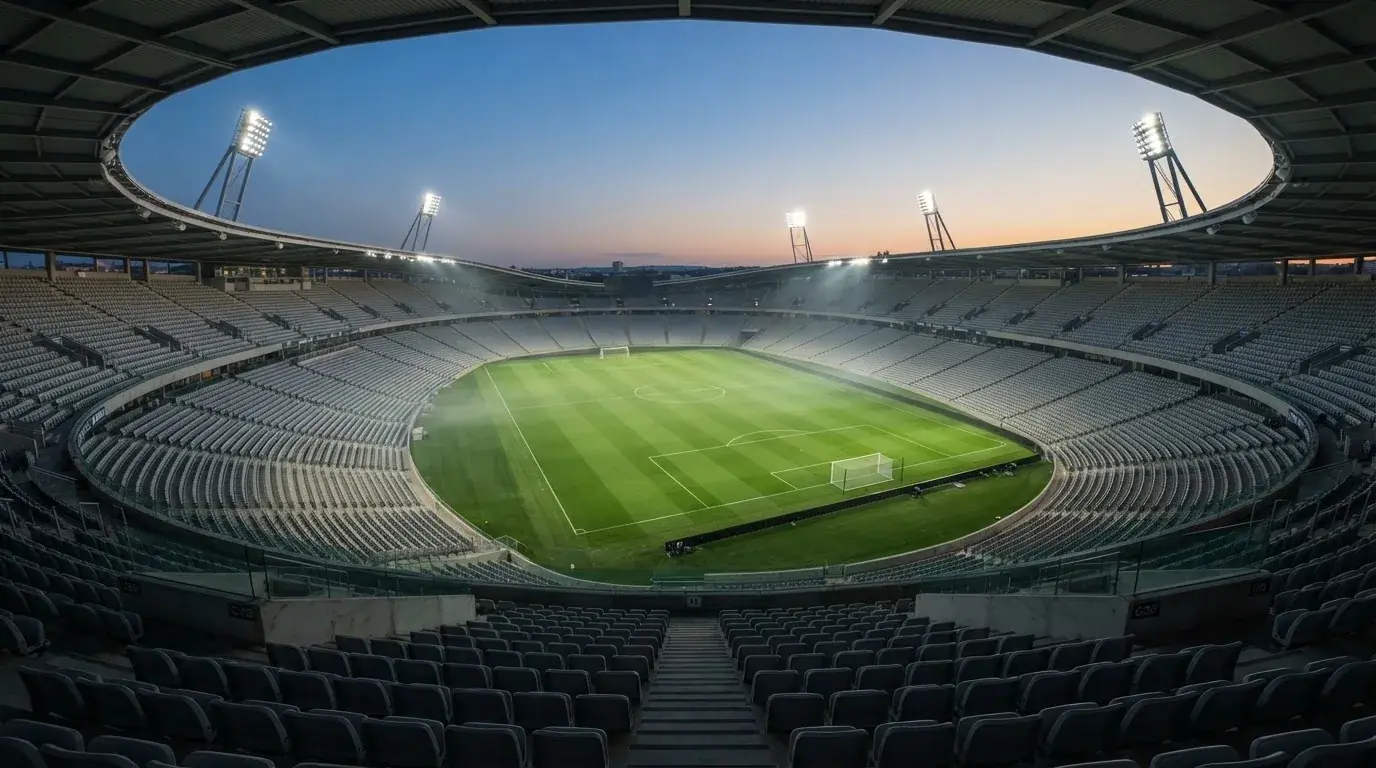 Een leeg voetbalstadion met lichtmasten bij schemering