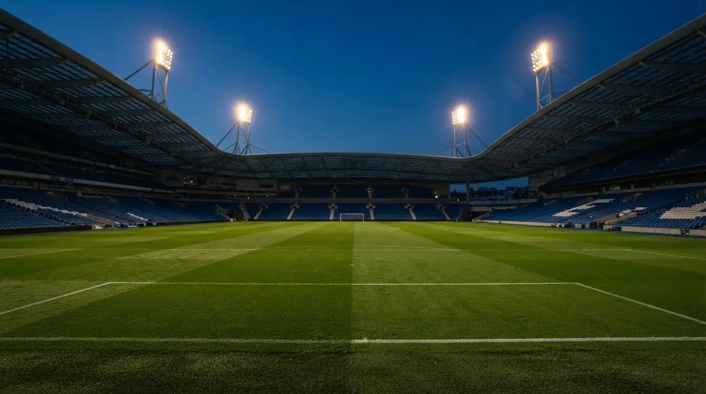 Een leeg voetbalstadion met lichtmasten bij schemering