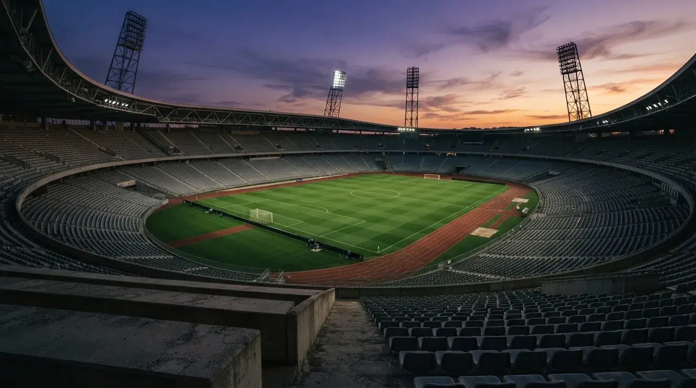 Een leeg voetbalstadion met lichtmasten bij schemering