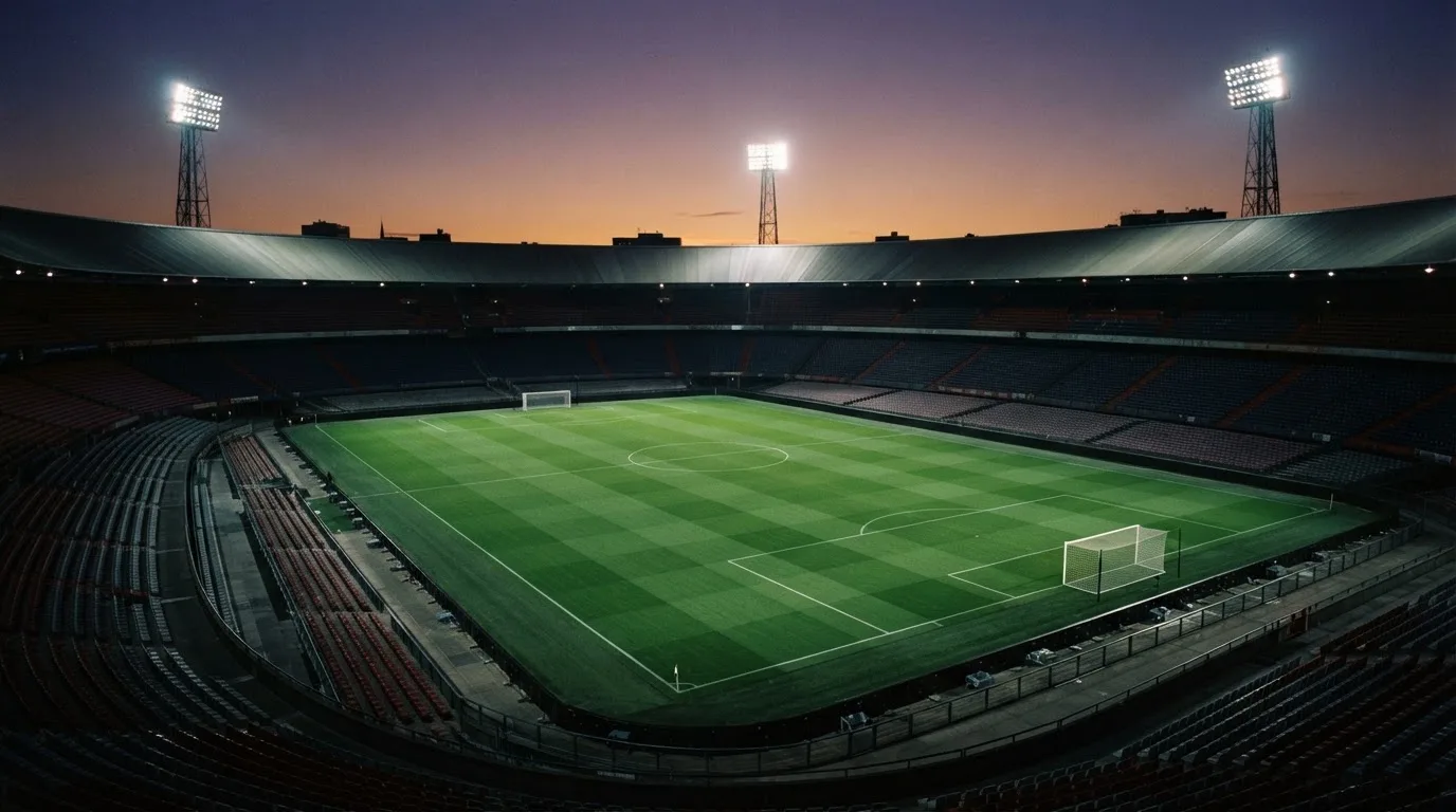Een leeg voetbalstadion met lichtmasten bij schemering
