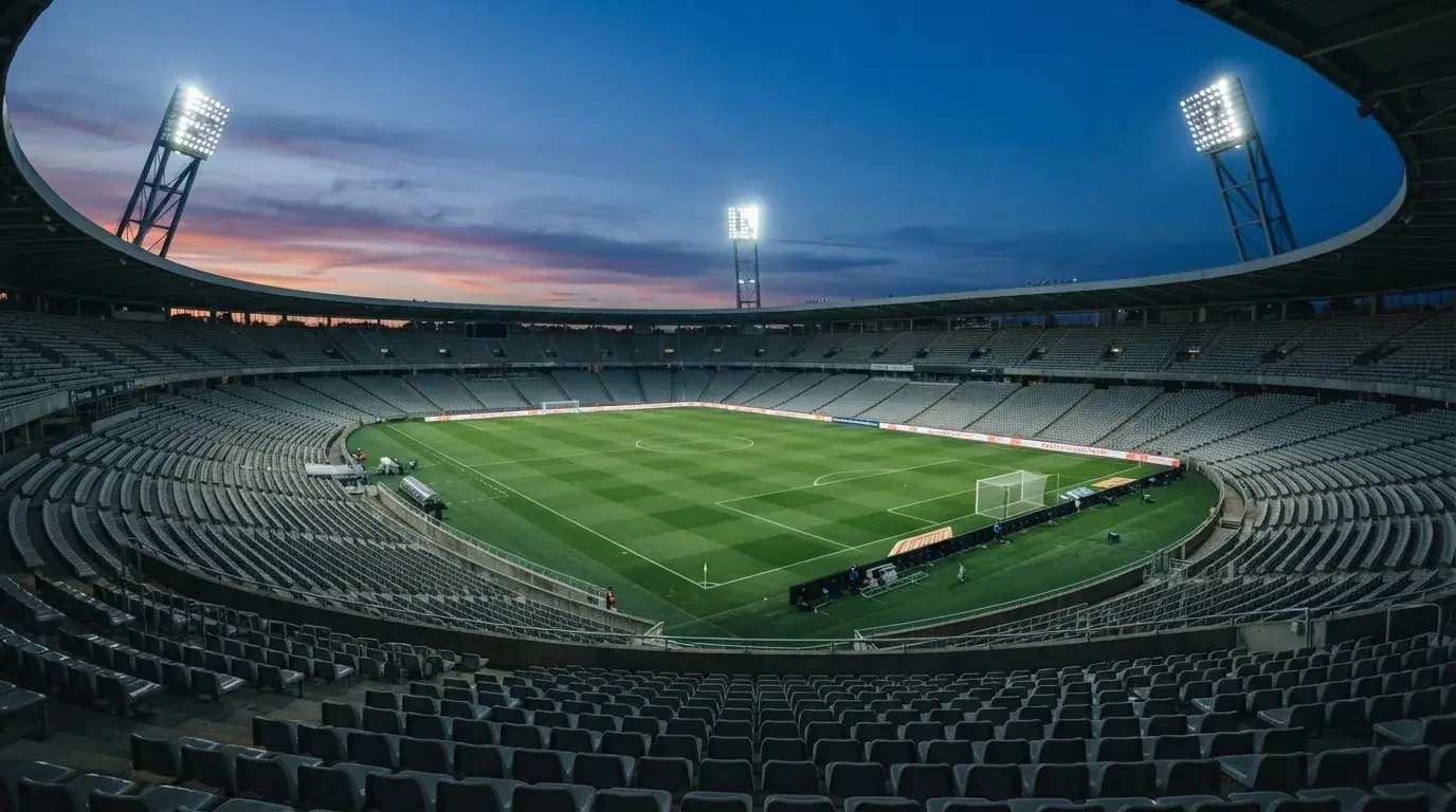 Een leeg voetbalstadion met lichtmasten bij schemering