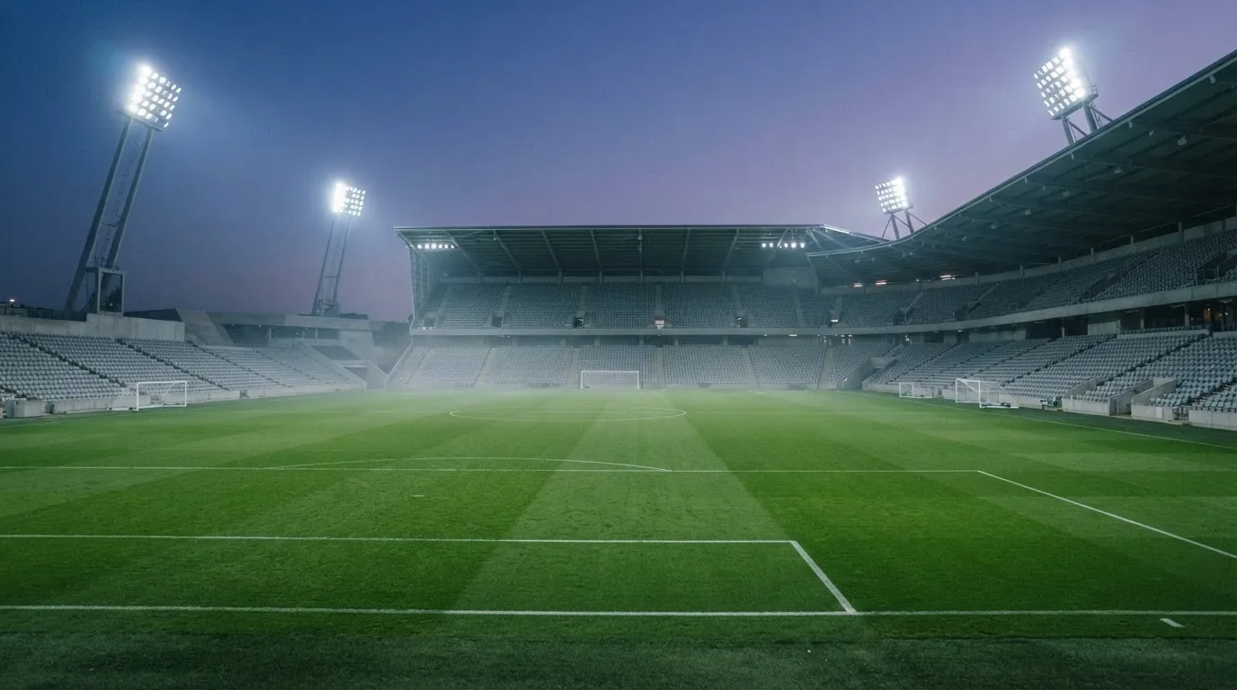 Een leeg voetbalstadion met lichtmasten bij schemering