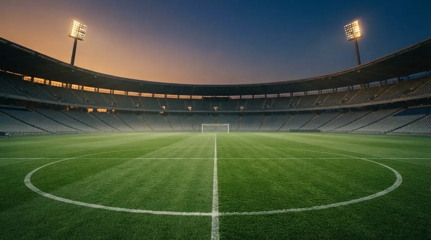Een leeg voetbalstadion met lichtmasten bij schemering