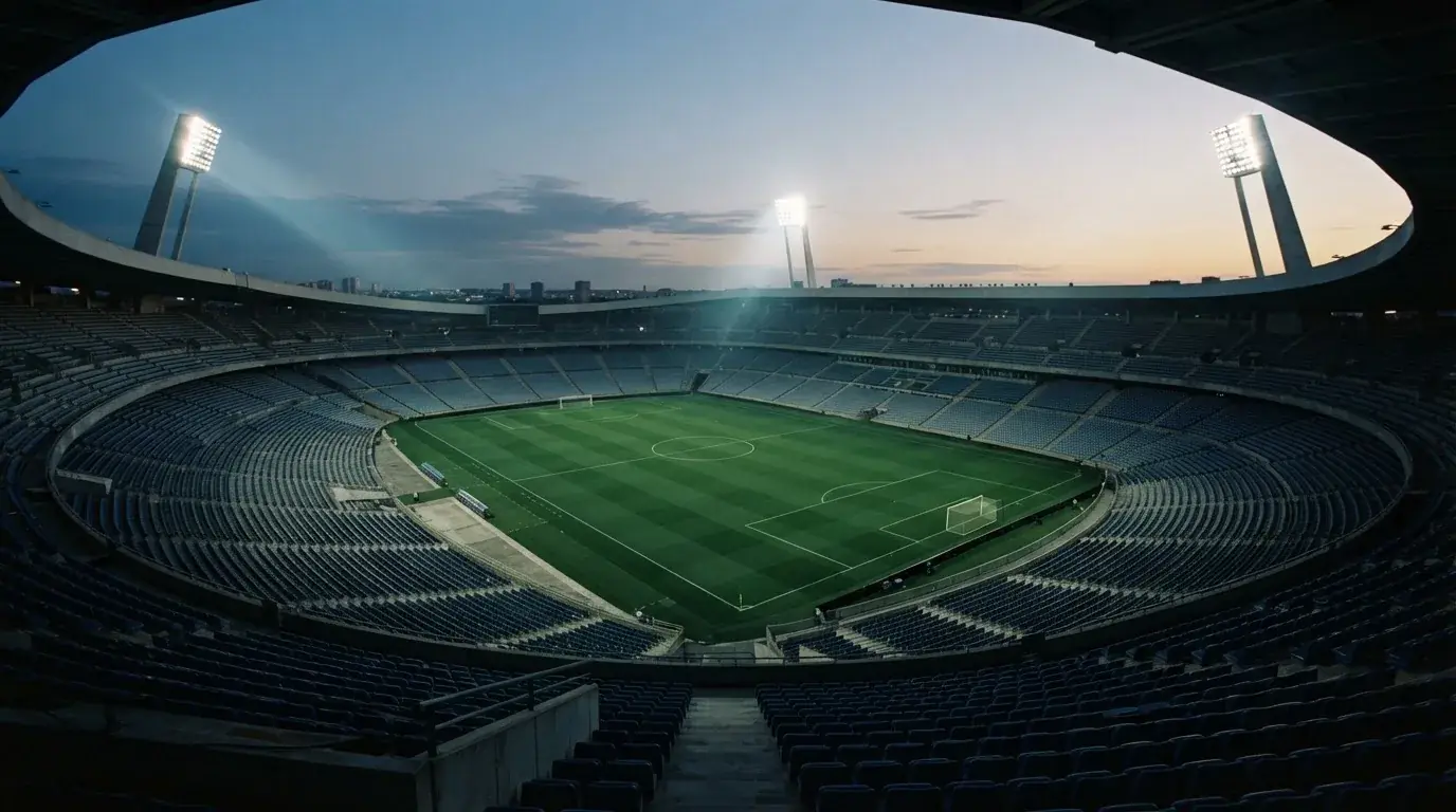 Een leeg voetbalstadion met lichtmasten bij schemering