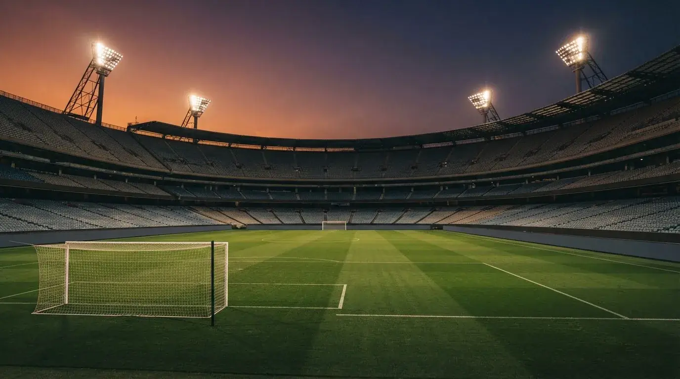 Een leeg voetbalstadion met lichtmasten bij schemering