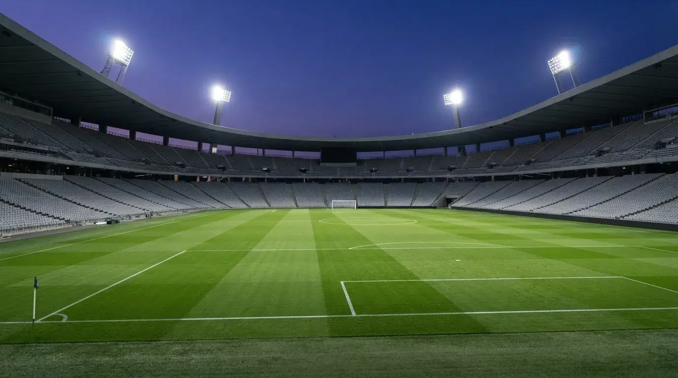 Een leeg voetbalstadion met lichtmasten bij schemering