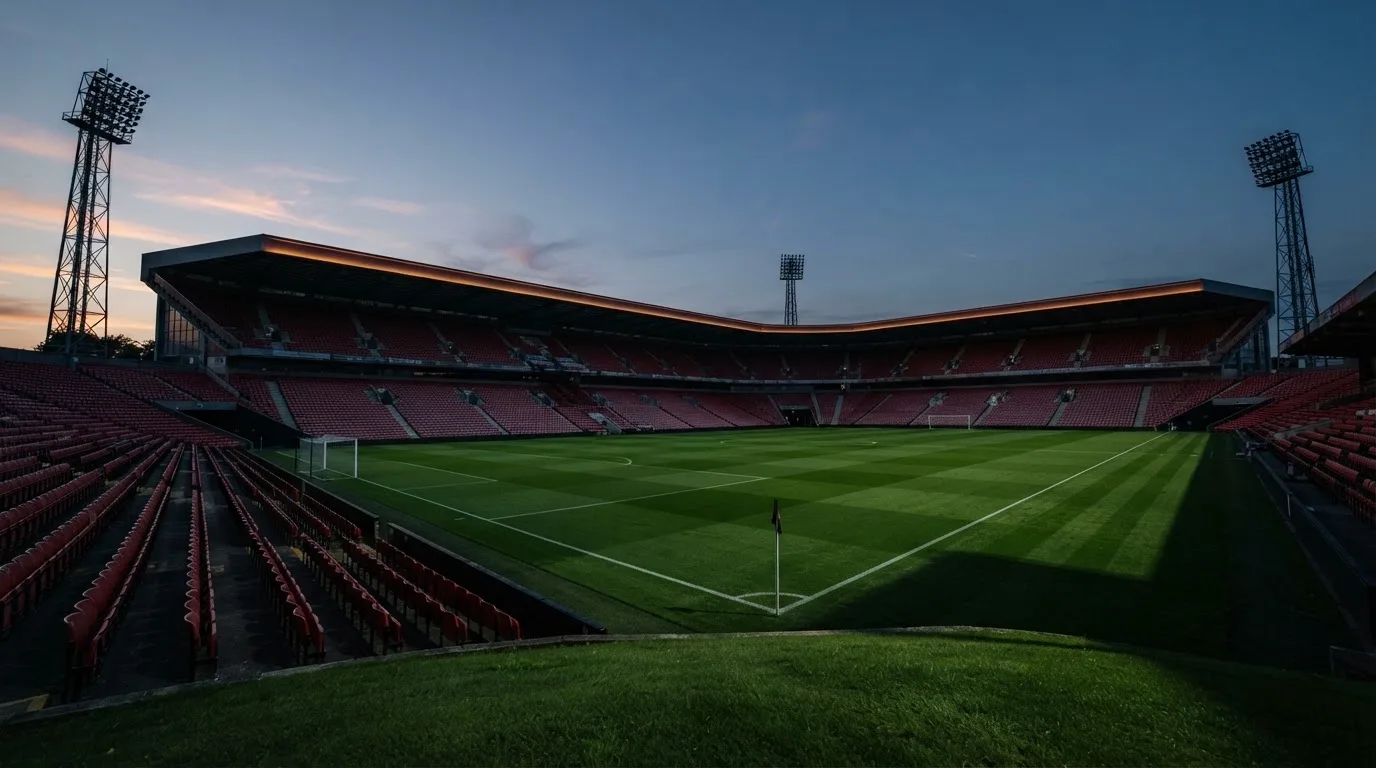 Een leeg voetbalstadion met lichtmasten bij schemering