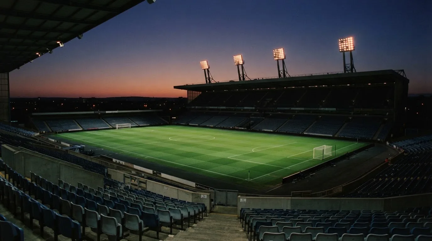 Een leeg voetbalstadion met lichtmasten bij schemering