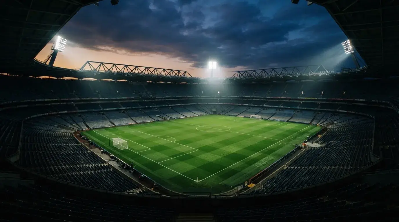 Een leeg voetbalstadion met lichtmasten bij schemering